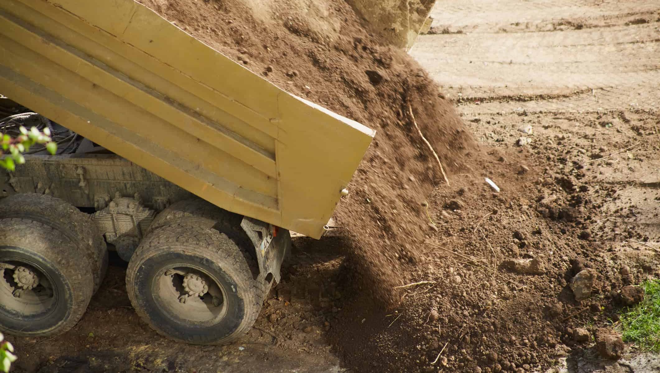 Lastebil tipper jordmasser som del av grunnarbeid og opparbeiding av nytt uteområde.