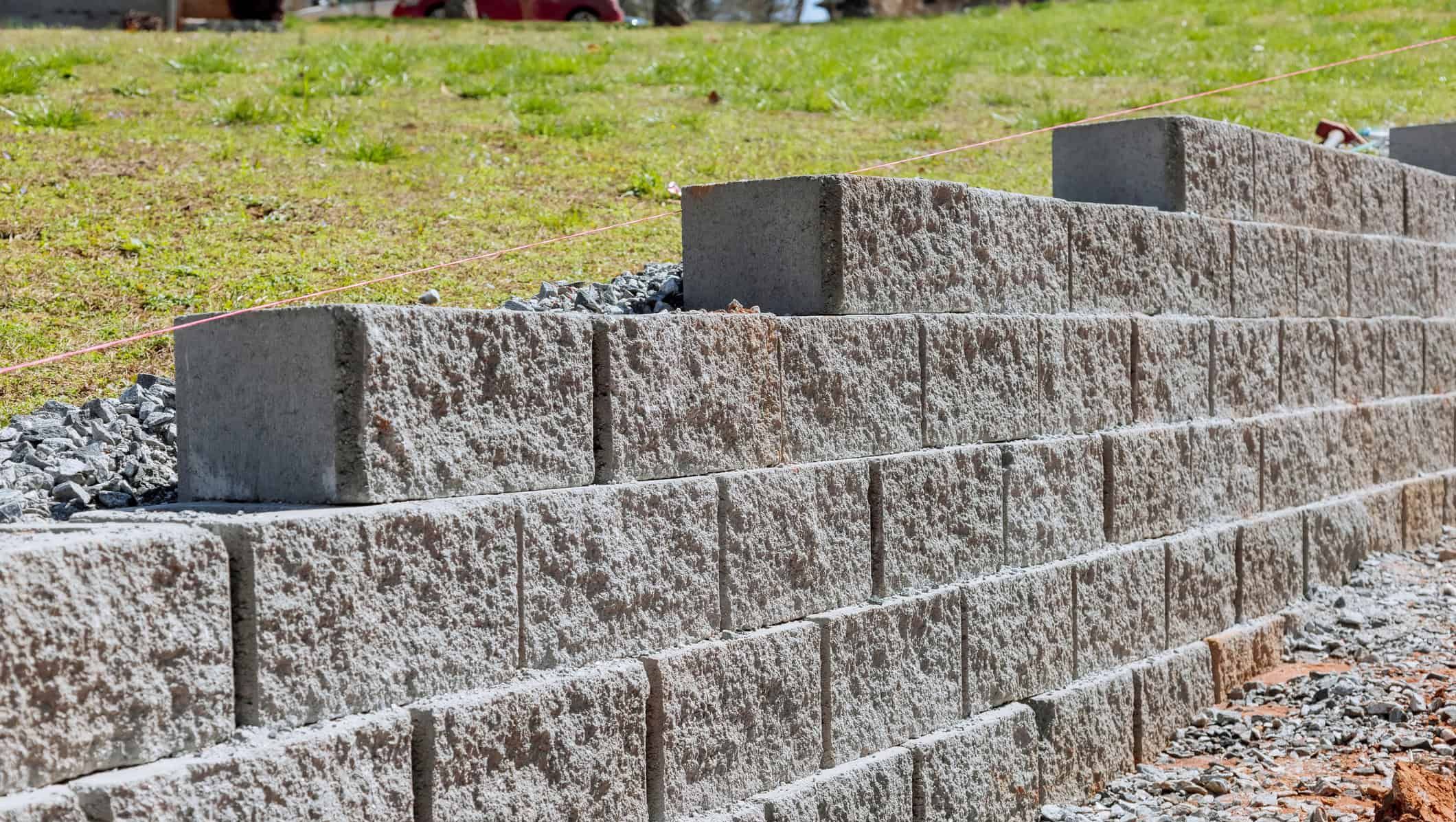 Støttemur av betongblokker bygges for å sikre terreng og skape nivåforskjeller utendørs.